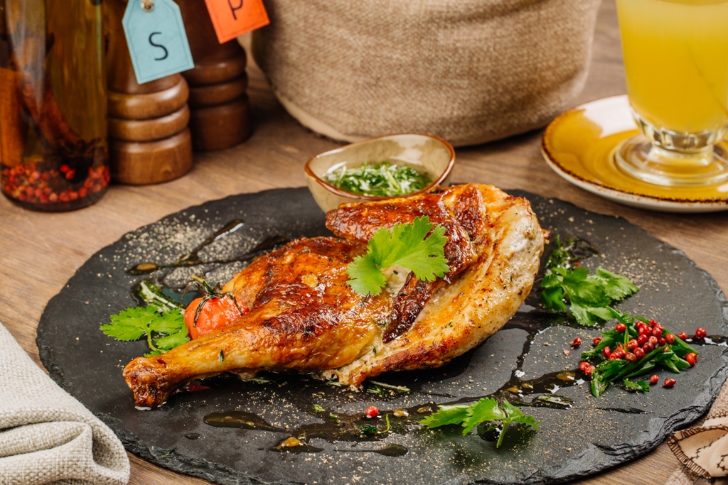 Grilled chicken Tabaka with sauce on stone plate.